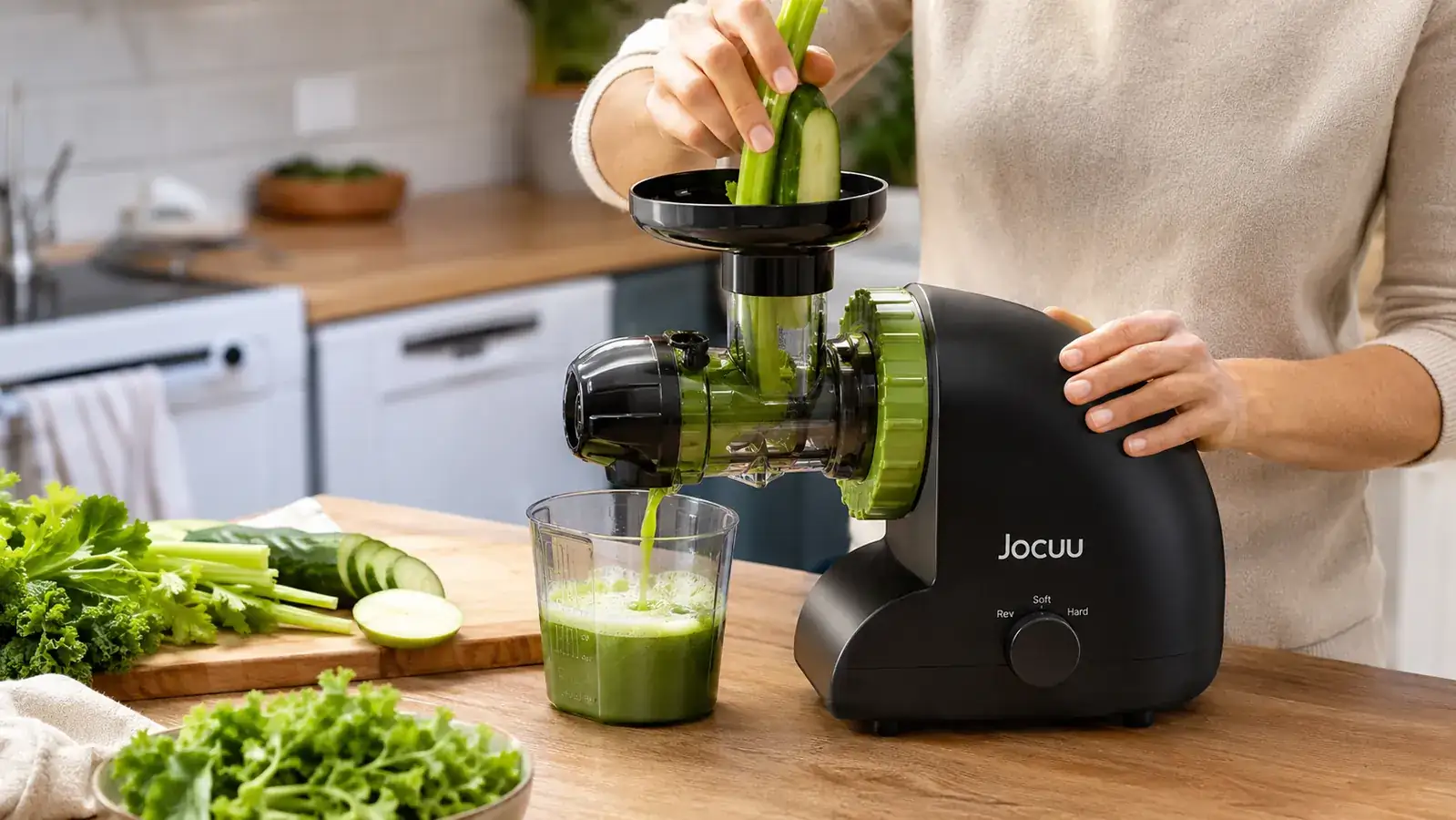 Hand feeding celery stalks into the Jocuu masticating juicer's chute before pressing the reverse function